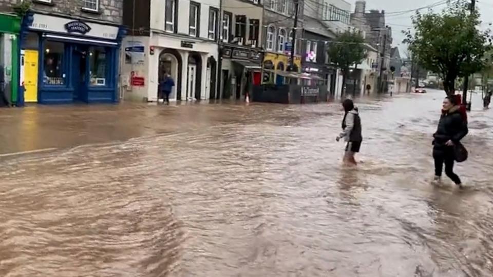 Two residents wade through floodwater in Cork as Storm Babet swept northwards across the country (PA)