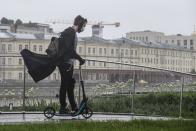 A man wearing a face mask and gloves to protect against coronavirus, rides a scooter in the rain along a boulevard in Moscow, Russia, on Tuesday, June 2, 2020. The authorities in Moscow allowed the city residents limited walks in the parks starting Monday for the first time since a tight lockdown was introduced in late March. (AP Photo/Alexander Zemlianichenko Jr)