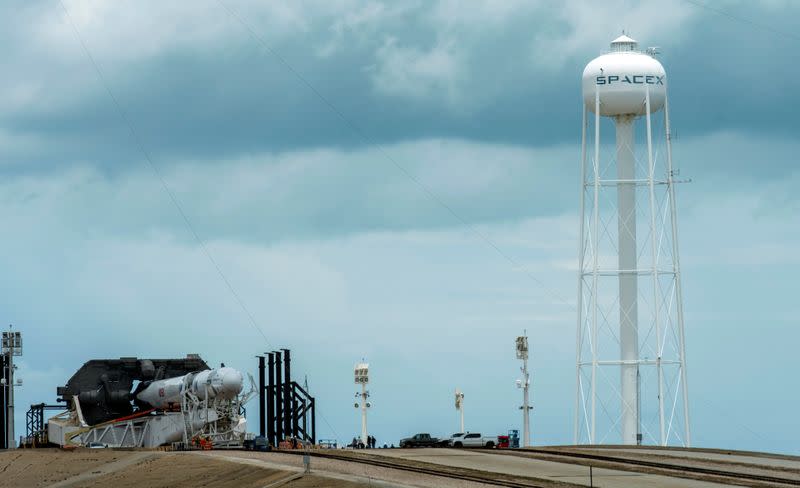 Crews work on the SpaceX Crew Dragon, attached to a Falcon 9 booster rocket, as it sits horizontal on Pad39A