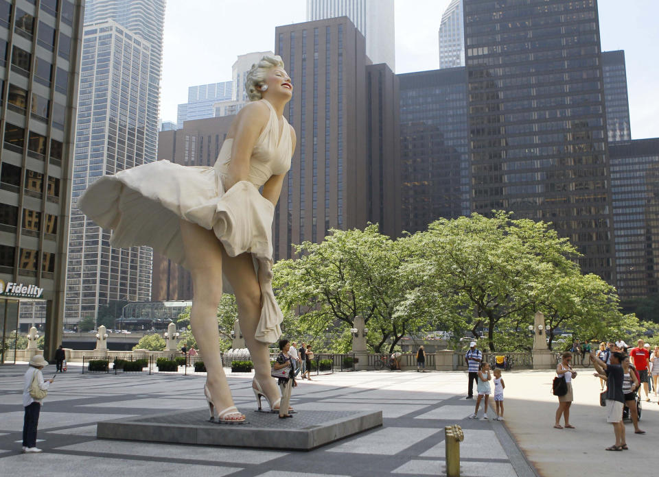 FILE - In this July 15, 2011 file photo, the curious gather around Seward Johnson's 26-foot-tall sculpture of Marilyn Monroe, in her most famous wind-blown pose, on Michigan Avenue, in Chicago. After causing some controversy in Chicago, the statue now resides in Palm Springs, Calif. Monroe passed away a half-century ago this week, a murky death that remains one of Hollywood's most tantalizing mysteries. But look around: Her legend lives on, more vibrantly than ever. In a twist she surely would have appreciated, this 1950's bombshell has become a 21st-century pop culture phenom.(AP Photo/Charles Rex Arbogast, File)