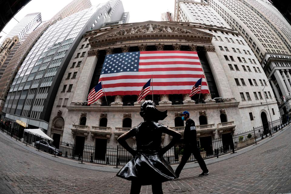 The fearless girl statue and the New York Stock Exchange (NYSE) are pictured on April 20, 2020 at Wall Street in New York City. - Wall Street opened lower on Monday as traders grappled with a drop in oil prices to 22-year lows as the coronavirus pandemic sapped demand for energy.