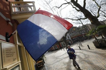 A woman walks past a national flag, the day before a general election, in Delft, Netherlands, March 14, 2017. REUTERS/Yves Herman