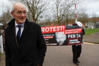 A protester holds a sign next to the Assange's father John Shipton while he leaves Belmarsh Prison after visiting Julian Assange, in London