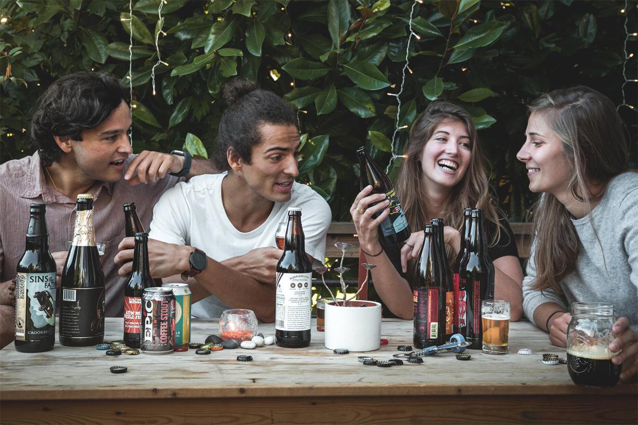 group of people sitting around a table drinking tavour beer