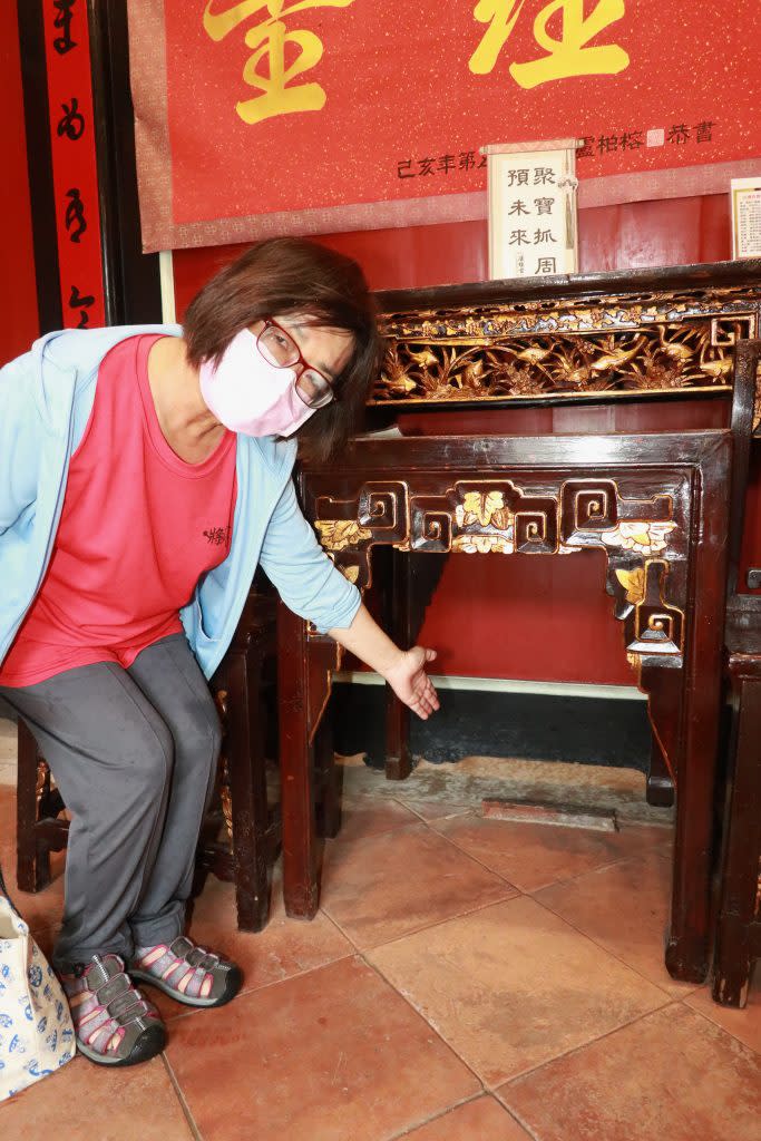 導覽老師郭麗桂所指為盧經堂大廳埋在桌下的地契石。（記者陳俊文攝）