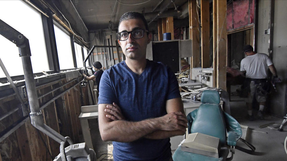 Dentist Ali Barbarawi poses on June 23, 2020, at his Chicago Lake Family Dental practice in Minneapolis, which was forced to close by the coronavirus pandemic, then destroyed in the unrest following the death of George Floyd at the hands of Minneapolis police. The destruction is a loss not just for him, but for his staff and patients, he said. Insurance will cover, at most, half of what he’ll need to rebuild, so on the advice of colleagues, he started a GoFundMe campaign to help bridge the gap. (AP Photo/Jim Mone)