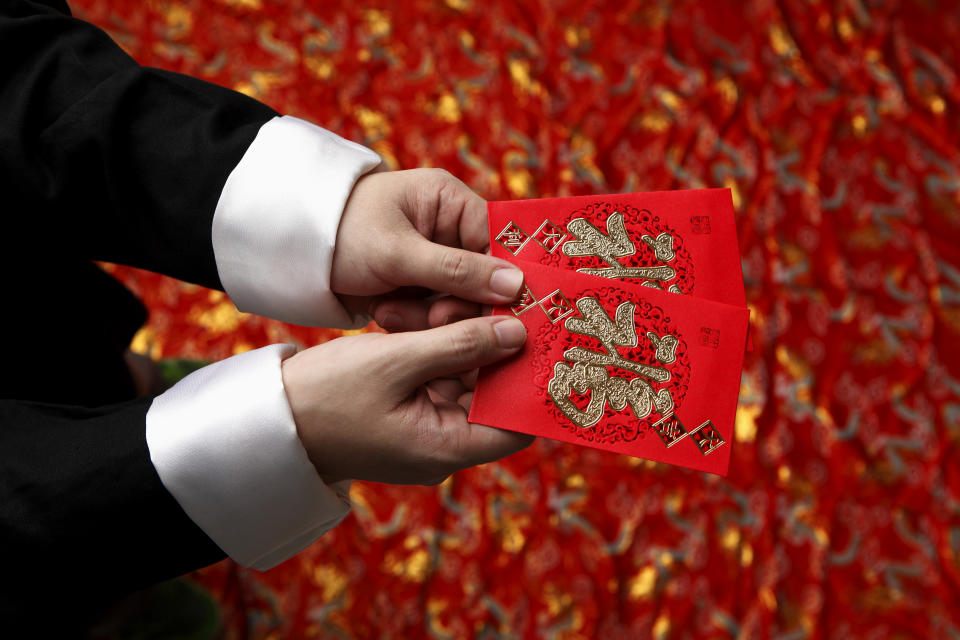A pair of hands holding up a lucky red packet, illustrating a story on MAS encouraging fit notes usage.