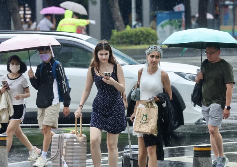 台北午後陣雨（2） 台北市區22日下午雲層密布，隨後下起陣雨，在西門 町商圈的外國遊客未備雨具，冒雨快步過馬路。 中央社記者張皓安攝  113年6月22日 