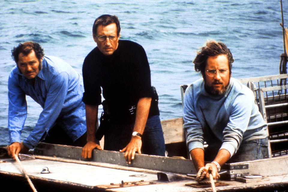 Three men stand on a boat