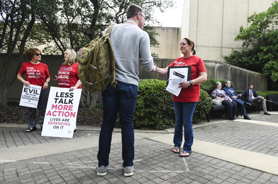 Jules Woodson, right, of Colorado Springs, Colo., hands out flyers while demonstrating outside the Southern Baptist Convention's annual meeting Tuesday, June 11, 2019, in Birmingham, Ala. First-time attendee Woodson spoke through tears as she described being abused sexually by a Southern Baptist minister. (AP Photo/Julie Bennett)