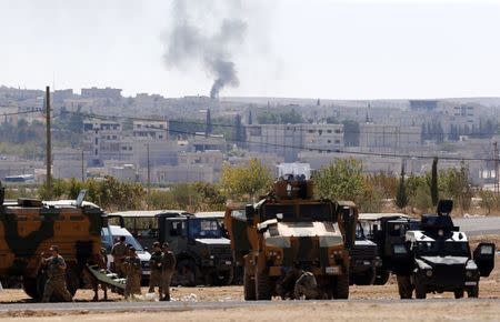 Smoke rises from the Syrian town of Kobani, seen from near the Mursitpinar border crossing on the Turkish-Syrian border in the southeastern town of Suruc, as Turkish soldiers stand guard on the Turkish side in Sanliurfa province October 5, 2014. REUTERS/Umit Bektas