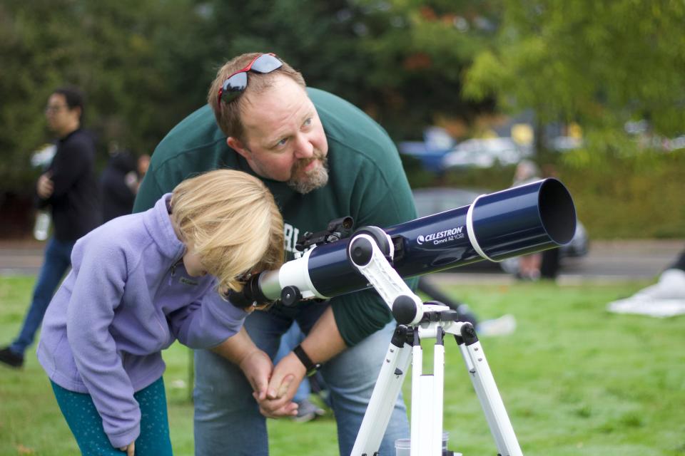 Ryan Rojas teaches his daughter Amelia how to look through their telescope as they wait for the annular solar eclipse at Eugene Science Center on Saturday, Oct. 14, 2023.