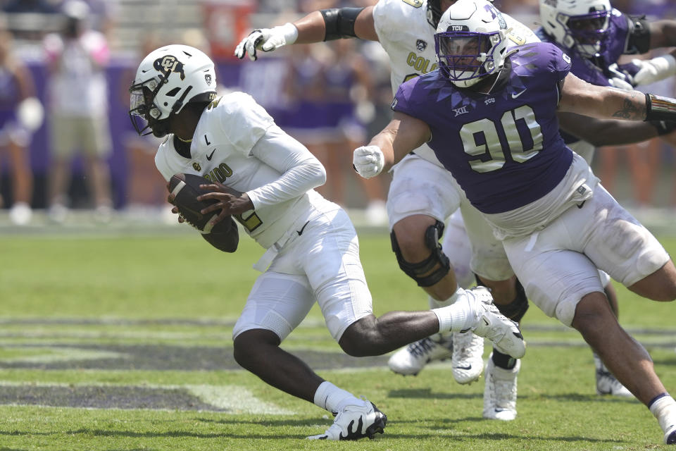 Colorado quarterback Shedeur Sanders (2) rolls out avoiding TCU defensive lineman Caleb Fox (90) during the second half of an NCAA college football game Saturday, Sept. 2, 2023, in Fort Worth, Texas. (AP Photo/LM Otero)