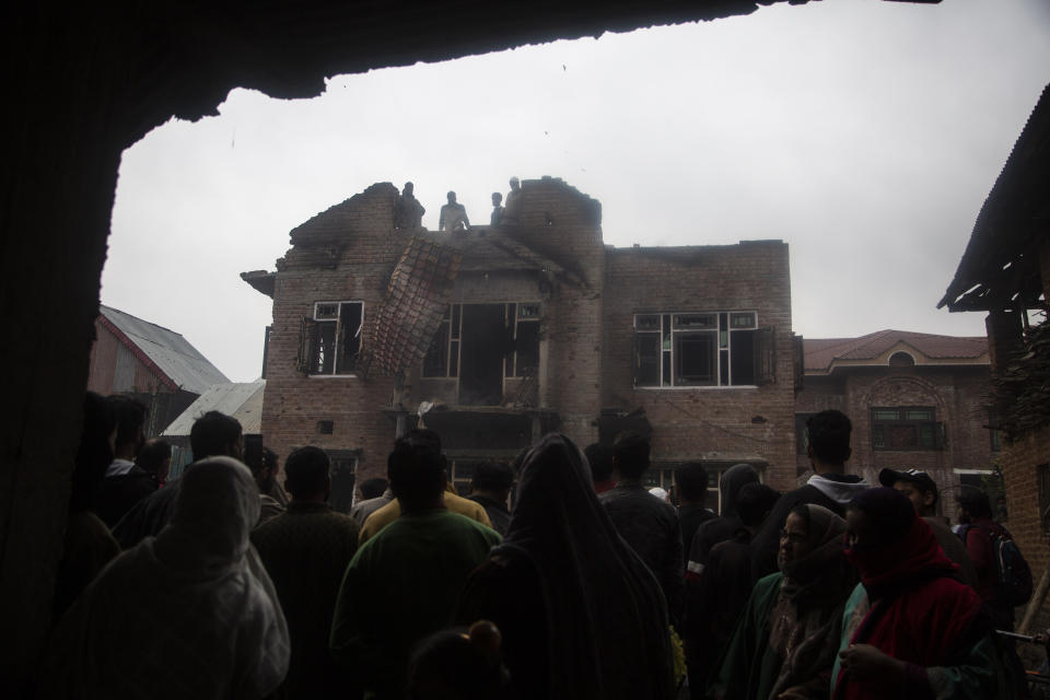 Kashmiri villagers gather near a house that was damaged during a gun battle between government forces and suspected rebels in Bijbehara, some 28 miles (45 kilometers) south of Srinagar, Indian controlled Kashmir, Sunday, April 11, 2021. (AP Photo/Mukhtar Khan)