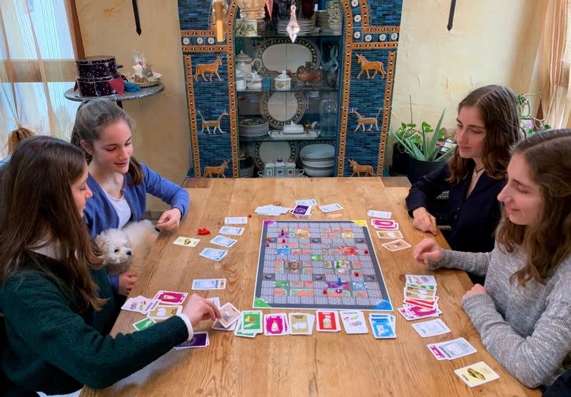 Rebecca, Lara, Stella y Sarah Schwaderlapp juegan 'Corona - el juego de mesa de la carrera hacia las tiendas' inventado por Lara y Sarah para pasar el tiempo encerrados, en Wiesbaden Biebrich, Alemania