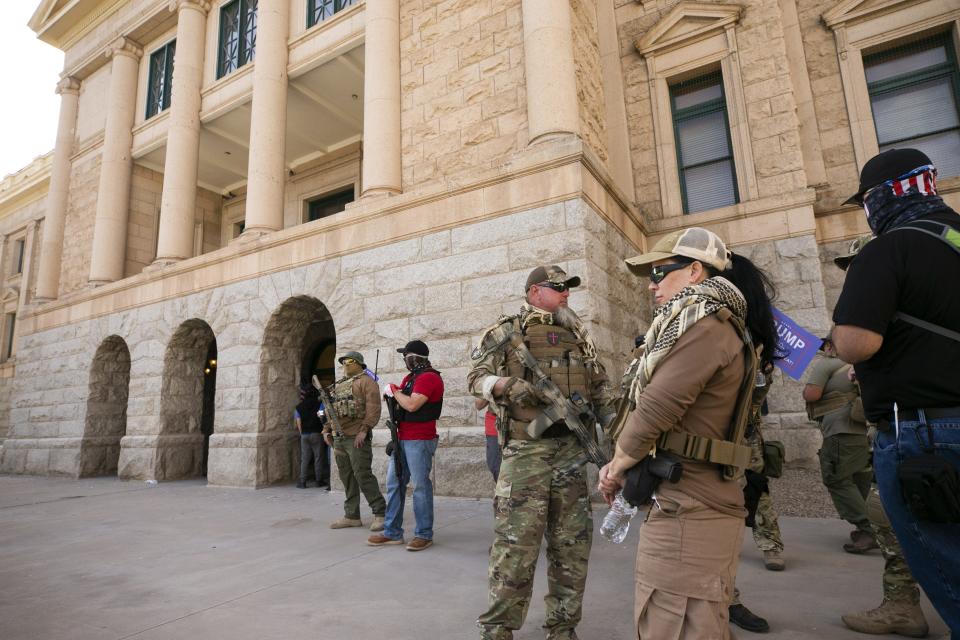 Armed individuals stand guard outside the state Capitol in Phoenix, during a pro-Trump rally, as the U.S. Congress meets in Washington, D.C., to certify the results of the presidential election, on Jan. 6, 2021.