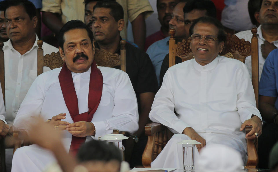 FILE - In this Nov. 5, 2018, file photo, Sri Lankan President Maithripala Sirisena, right, and his newly appointed prime minister Mahinda Rajapaksa, center attend a rally held outside the parliamentary complex as a police officer tries to control the crowd in Colombo, Sri Lanka. Government dysfunction and an intelligence failure that preceded the Easter Sunday bombings that killed 253 people in Sri Lanka are traced to simmering divisions between the president and prime minister after a weekslong political crisis that crippled the country last year. (AP Photo/Eranga Jayawardena, File)