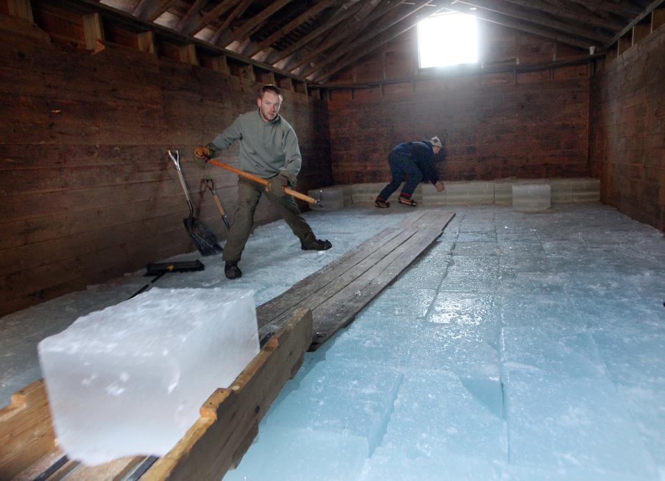 Douglas Adams, left, gets ready to grab a sliding block of ice as Parker Hansen stacks in the ice house at the Rockywold-Deephaven Camp in Holderness, N.H.,Thursday, Jan. 9, 2014. For more than a century ice from Squam Lake has been used to keep ice boxes cool for summer residents at the camp. (AP Photo/Jim Cole)