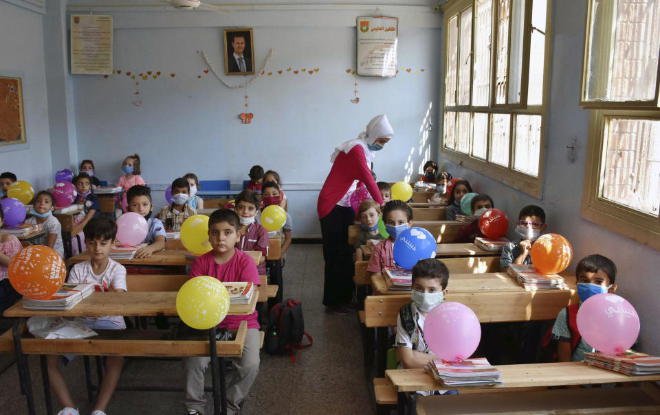 In this photo released by the Syrian official news agency SANA, students attend a lesson on their first day back at school, in Homs, Syria, Sunday, Sept. 13, 2020. More than 3 million students went to school in government-held areas around Syria Sunday marking the first school day amid strict measures to prevent the spread of coronavirus. (SANA via AP)