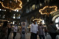 People visit the Byzantine-era Hagia Sophia, an UNESCO World Heritage site and one of Istanbul's main tourist attractions in the historic Sultanahmet district of Istanbul, Friday, July 10, 2020. Turkey's highest administrative court issued a ruling Friday that paves the way for the government to convert Hagia Sophia - a former cathedral-turned-mosque that now serves as a museum - back into a Muslim house of worship. The Council of State threw its weight behind a petition brought by a religious group and annulled a 1934 cabinet decision that changed the 6th century building into a museum. (AP Photo/Emrah Gurel)