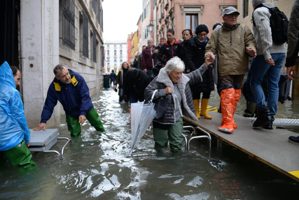 People walk on a trestle bridge during high water, in Venice, northern Italy, Friday, Nov. 15, 2019. Exceptionally high tidal waters returned to Venice on Friday, prompting the mayor to close the iconic St. Mark’s Square and call for donations to repair the Italian lagoon city just three days after it experienced its worst flooding in 50 years. (Andrea Merola/ANSA via AP)