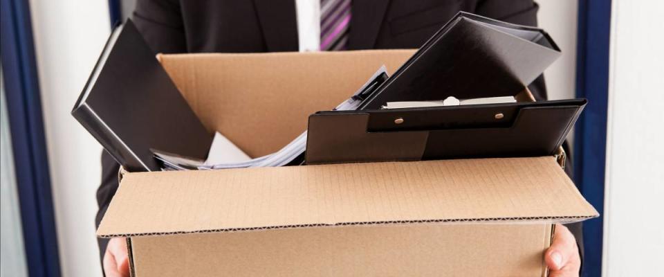 Portrait of young businessman holding cardboard in office