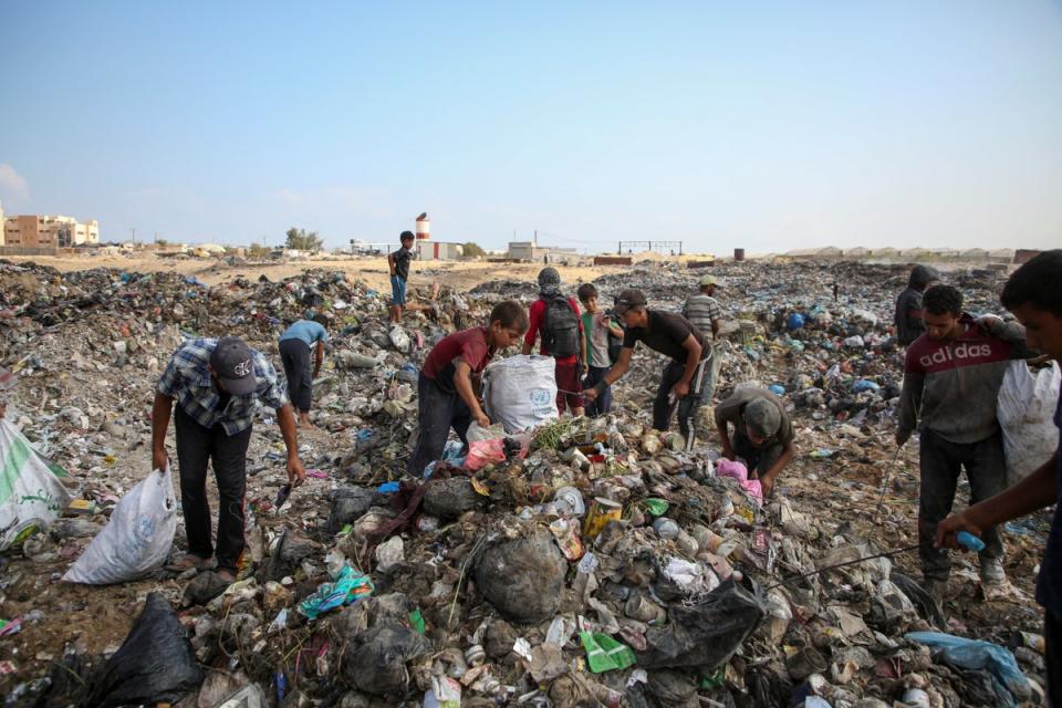 Displaced Palestinians scavange for usable items at a rubbish dump in Khan Younis (Reuters)