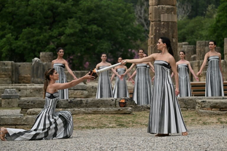 La actriz griega Mary Mina (tercera por la derecha), en el papel de sacerdotisa, enciende la antorcha durante la ceremonia de encendido de la llama olímpica de los Juegos de París-2024, en la antigua Olimpia, en Grecia, el 16 de abril de 2024 (Aris MESSINIS)