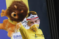 Stage winner and new overall leader, wearing the yellow jersey, celebrates with the mascot on the podium after stage 20 of the Tour de France cycling race, an individual time trial over 36.2 kilometers (22.5 miles), from Lure to La Planche des Belles Filles, France, Saturday, Sept. 19, 2020. (AP Photo/Christophe Ena, Pool)