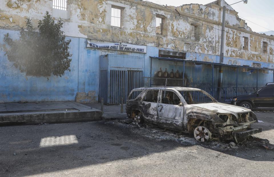 A burned car is seen outside the National Penitentiary in downtown Port-au-Prince, Haiti, Sunday, March 3, 2024. Hundreds of inmates have fled Haiti's main prison after armed gangs stormed the facility overnight. (AP Photo/Odelyn Joseph)