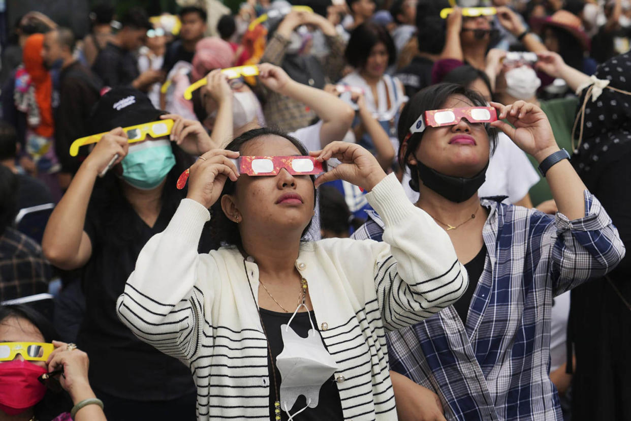 People wear protective glasses to watch a solar eclipse in Jakarta, Indonesia, on April 20, 2023. (Tatan Syuflana / AP file)