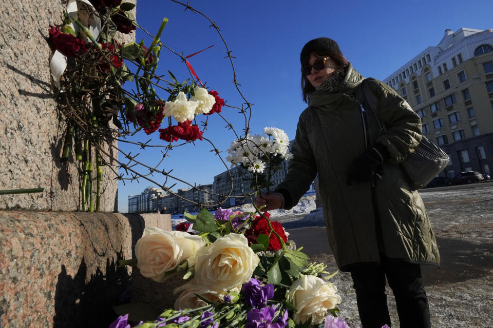 A woman lays flowers paying respect to Alexei Navalny at the Memorial to Victims of Political Repression in St. Petersburg, Russia, Monday, Feb. 19, 2024. Russians across the vast country streamed to ad-hoc memorials with flowers and candles to pay tribute to Alexei Navalny, the most famous Russian opposition leader and the Kremlin's fiercest critic. Russian officials reported that Navalny, 47, died in prison on Friday. (AP Photo/Dmitri Lovetsky)