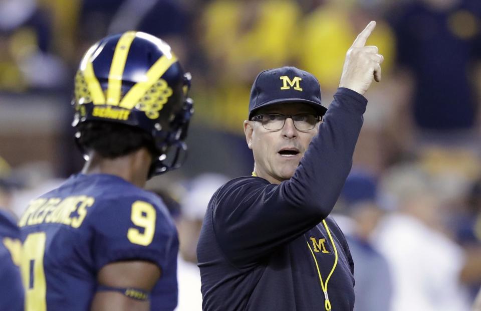 Michigan head coach Jim Harbaugh, right, signals to his team during warmups for an NCAA college football game against Michigan State, Saturday, Oct. 7, 2017, in Ann Arbor, Mich. (AP Photo/Carlos Osorio)