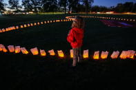 A child stands nexto to candles placed around a banner during a vigil on Canada's first National Day for Truth and Reconciliation, honouring the lost children and survivors of Indigenous residential schools, their families and communities, at Chiefswood Park in Ohsweken, Ontario, Canada September 30, 2021. REUTERS/Carlos Osorio