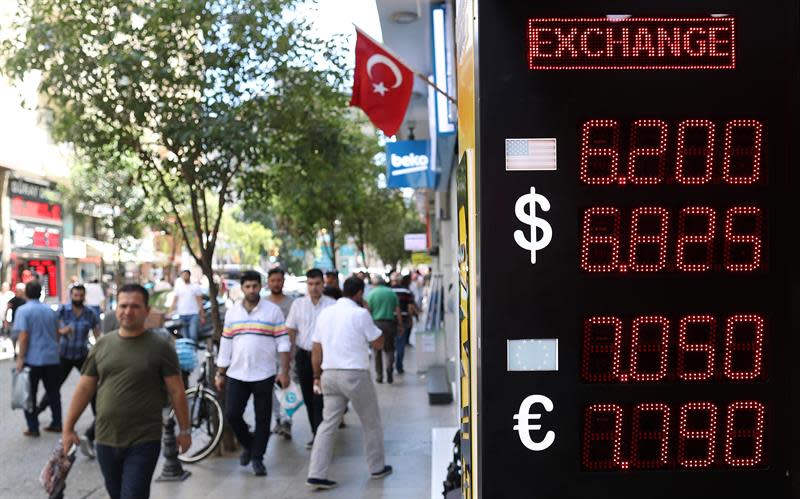 Ciudadanos pasean junto a un centro de cambio de divisas cuenta dólares americanos en Estambul, Turquía, el lunes 13 de agosto de 2018. EFE