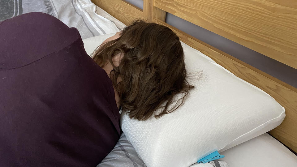 The reviewer lying on the Levitex Sleep Posture Pillow in the side sleeping position