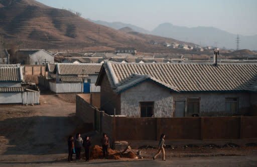 Local residents are seen from the window of a train, at a small villlage along the railway heading from Pyongyang to the North Pyongan Province on the west coast, on April 8