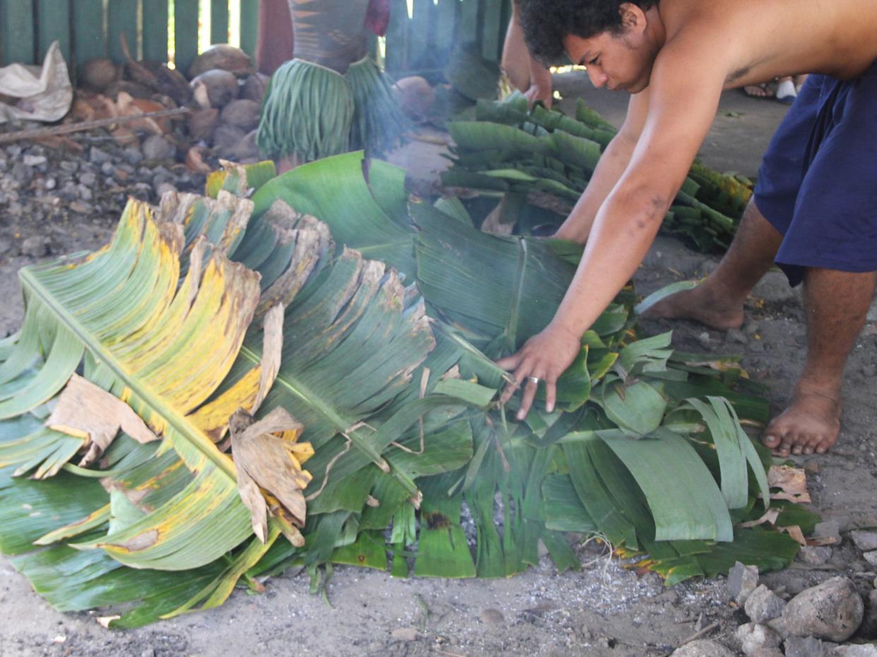 Close up of umu cooking.Food is cooked by covering it with hot stones and coconut frond mats, which keep in the heat and the smoke.