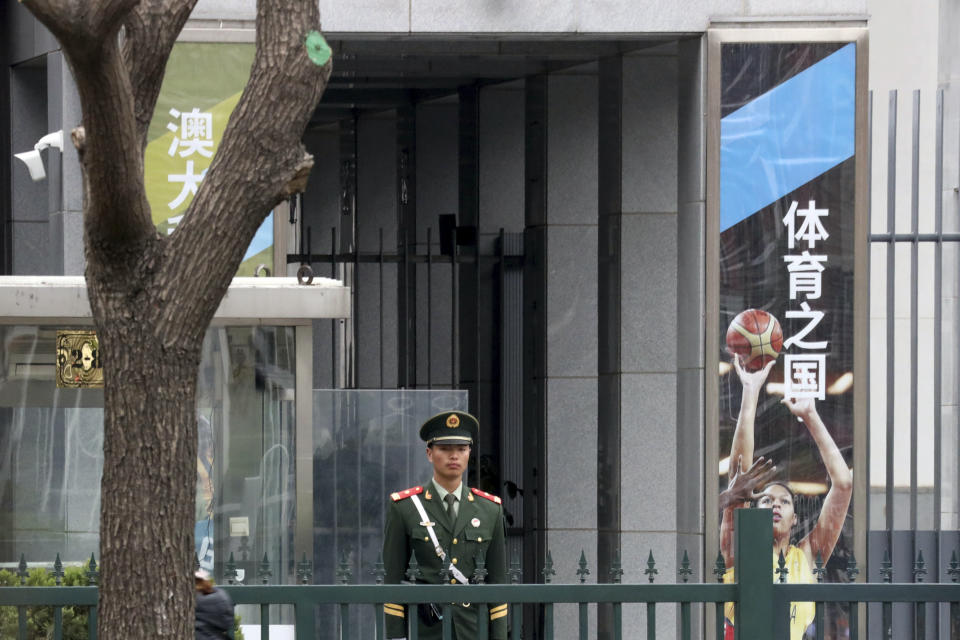 A Chinese paramilitary man guards the entrance to the Australian embassy in Beijing, China, Tuesday, April 9, 2019. A security adviser to an Australian prime minister said he warned a Chinese-Australian writer not to travel to China before the blogger and critic of China's Communist Party was detained on arrival at a Chinese airport in January. (AP Photo/Ng Han Guan)