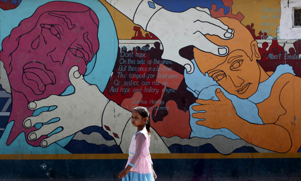 In this photo taken Monday, March 12, 2012, a girl walks past a mural at a shanty near the abandoned Union Carbide factory at J.P. Nagar, a neighborhood that was affected by the 1984 gas leak because of its proximity to the factory in Bhopal, India. The survivors of the tragedy of 27 years ago, with their lingering illnesses, sick children and dead relatives, faded away from the world's memory, even as their suffering went on. Now, though, they have seized on a new chance to force their plight in front of the world, the London Olympics. (AP Photo/Rafiq Maqbool)