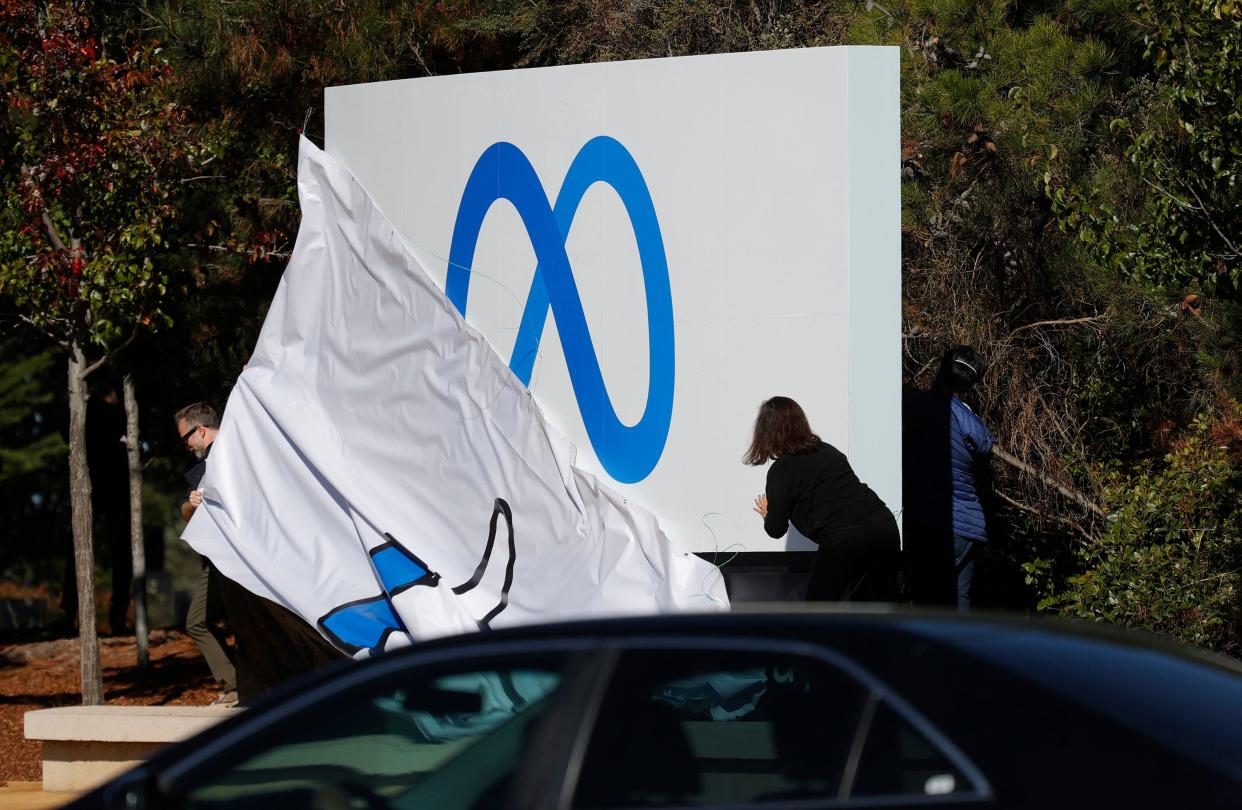 Facebook employees unveil a new logo and the name "Meta" on the sign in front of Facebook headquarters on Oct. 28 in Menlo Park, California.