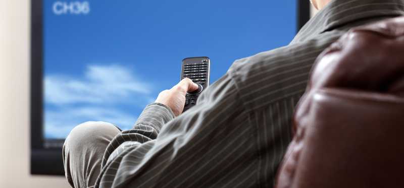 A man sitting in front of TV with remote in hand.