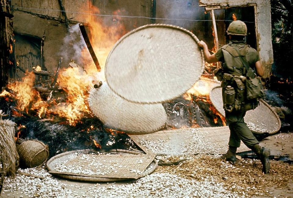 An American soldier stokes the flames of houses that were burned during the massacre in My Lai on March 16, 1968.