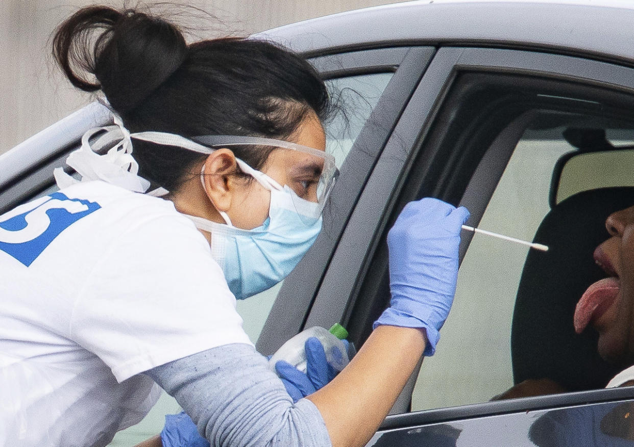 A medical worker takes a swab at a drive-in coronavirus testing facility at the Chessington World of Adventures Resort in Chessington, England, Wednesday April 29, 2020. Coronavirus testing is now available for more people in England from Wednesday as the government relaxed rules on eligibility. (Aaron Chown/PA via AP)