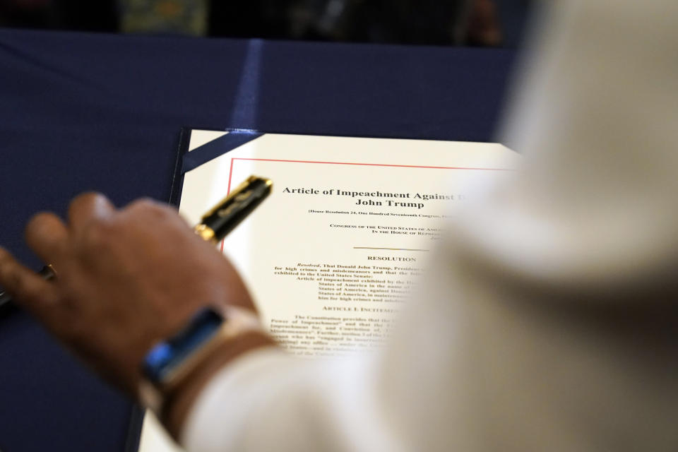 Staff member Latrice Powell placed the article of impeachment against Trump on a table for Pelosi to sign. (Photo: Alex Brandon/Associated Press)