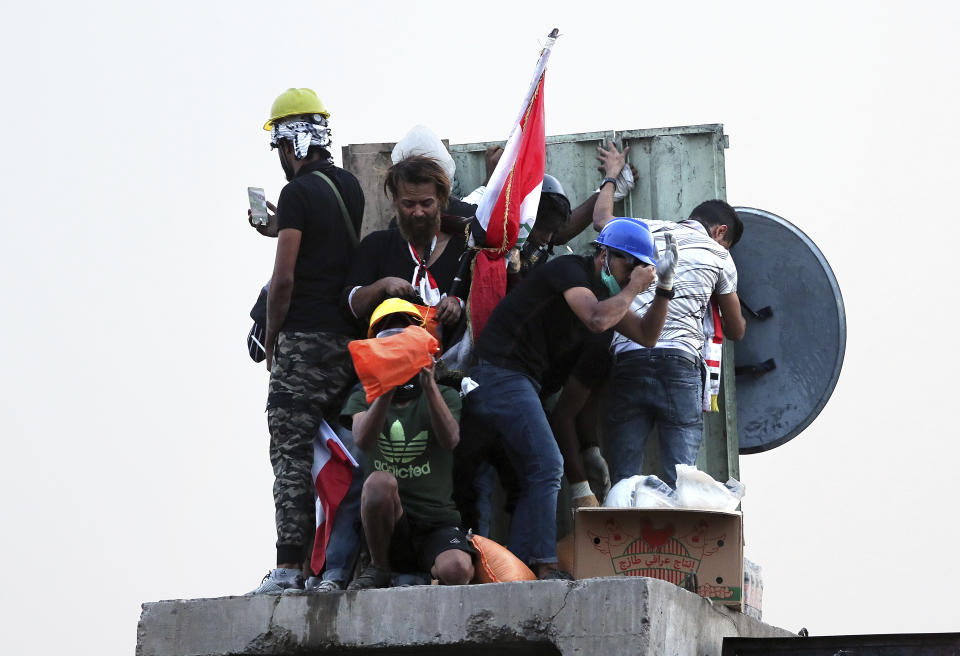 Anti-government protesters control the barriers while Iraqi security forces fire tear gas and close the bridge leading to the Green Zone, during a demonstration in Baghdad, Iraq, Tuesday, Oct. 29, 2019. (AP Photo/Hadi Mizban)