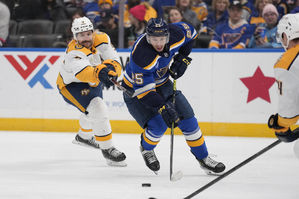 St. Louis Blues' Jordan Kyrou (25) and Nashville Predators' Filip Forsberg (9) battle for a loose puck during the second period of an NHL hockey game on Friday, Nov. 24, 2023, in St. Louis. (AP Photo/Jeff Roberson)