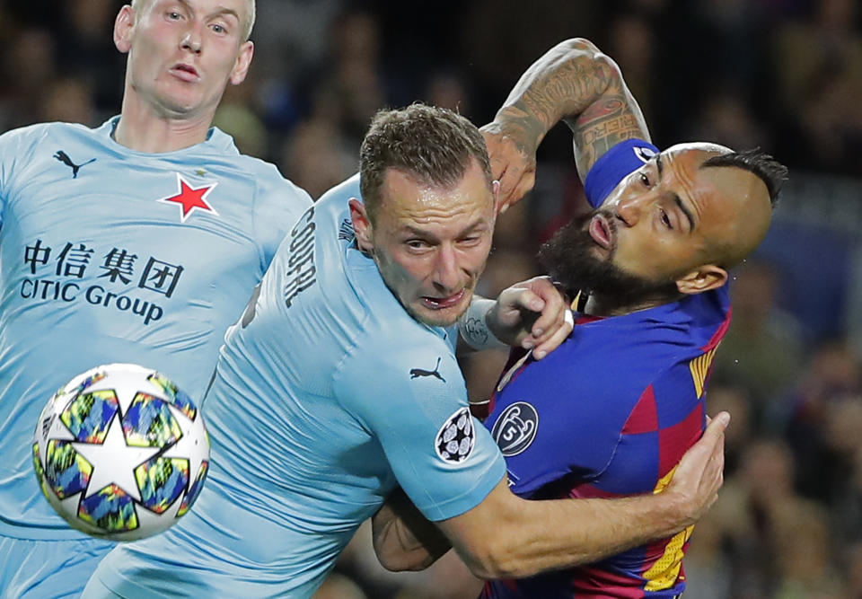 Vladmir Coufal (centro) del Slavia Praga trata de contener a Arturo Vidal del Barcelona en el partido por la Liga de Campeones, el martes 5 de noviembre de 2019. (AP Foto/Emilio Morenatti)