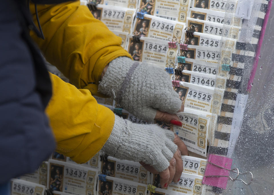 Una vendedora de lotería coloca boletos en Madrid, el sábado 21 de diciembre de 2019. (AP Foto/Paul White)