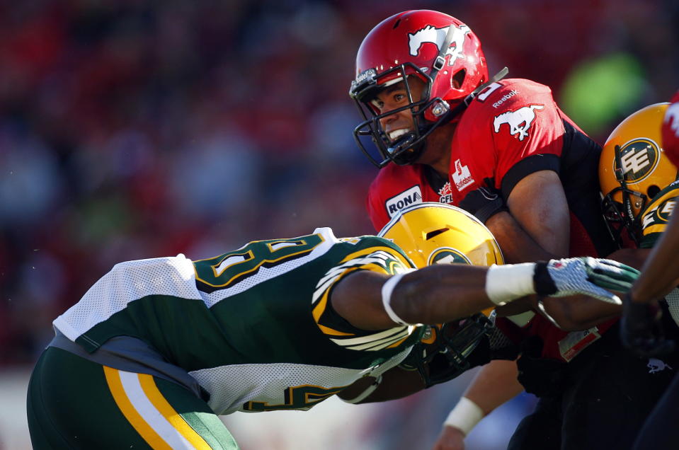 Edmonton Eskimos' Cary Koch, left, tackles Calgary Stampeders' Jon Cornish, during first half CFL pre-season football action in Calgary, Alta., Friday, June 15, 2012. THE CANADIAN PRESS/Jeff McIntosh